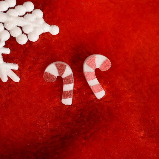 Red and white striped candy cane earrings on a plush red background.