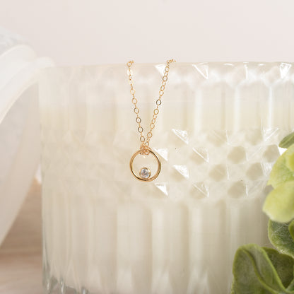 Gold necklace with a small pendant on a white candle