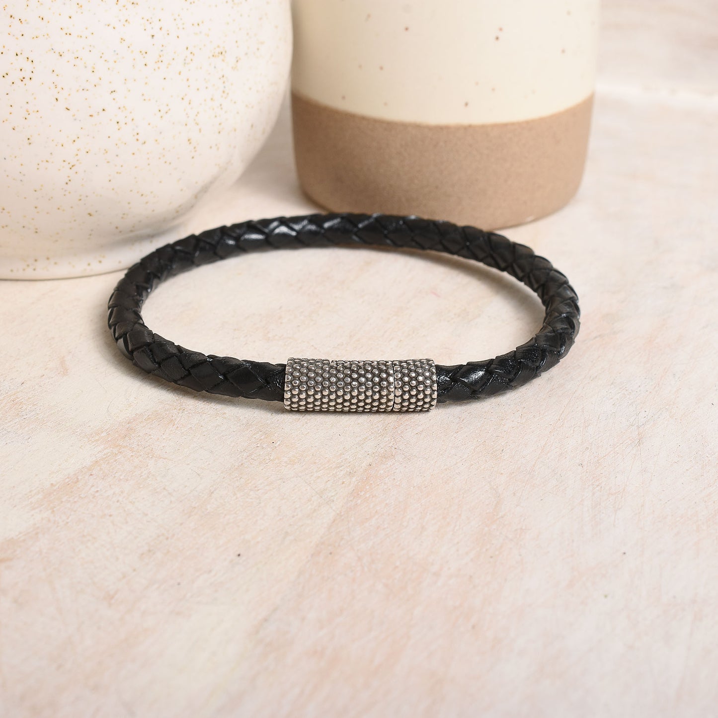 Round braided leather in black with a dotted silver clasp.