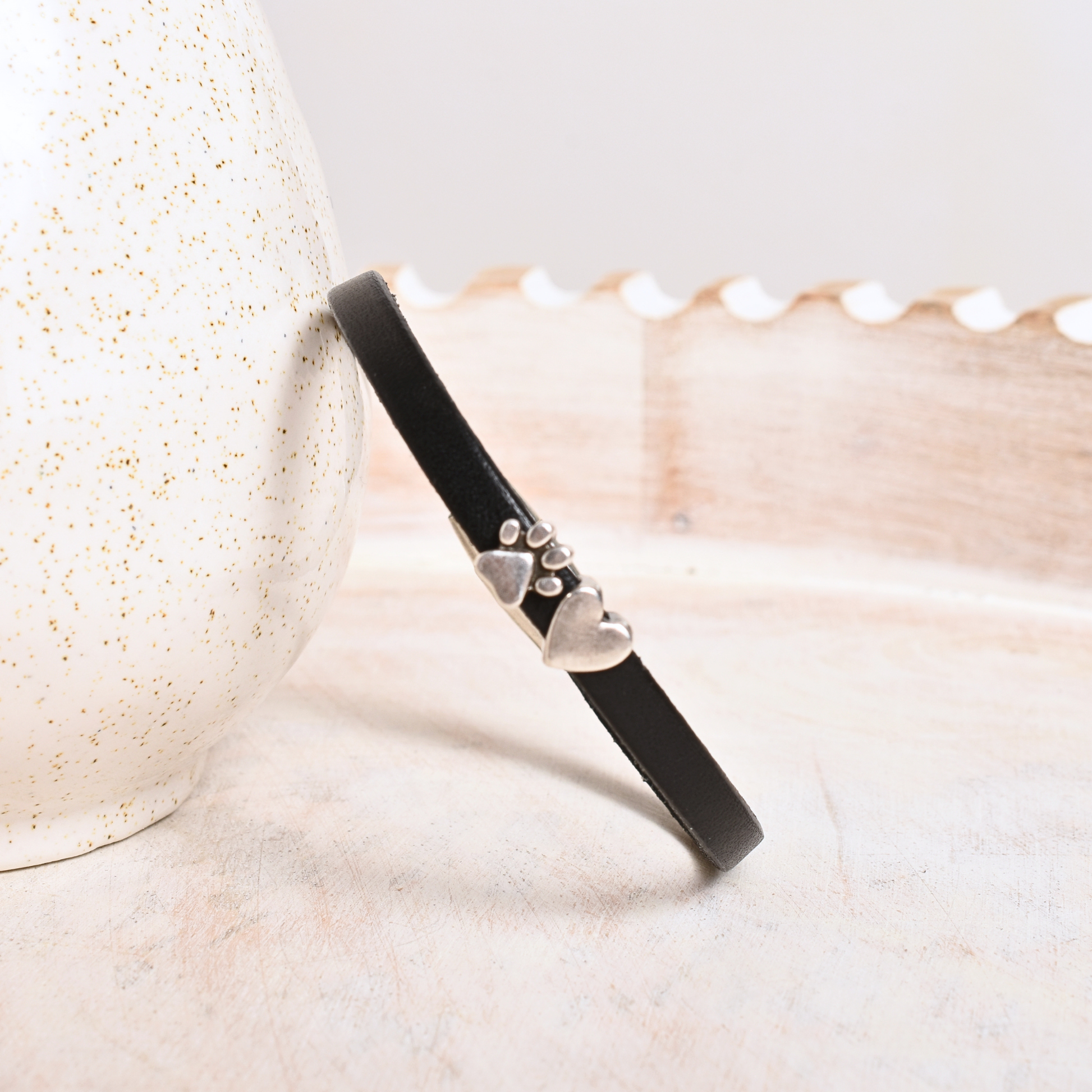 Black bracelet with paw print design on a shell background