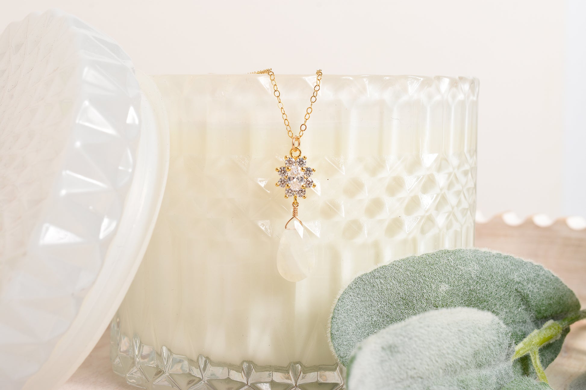 Gold necklace with a star-shaped pendant and moonstone suspended from a candle