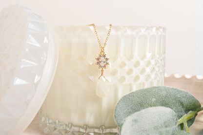 Gold necklace with a star-shaped pendant and moonstone suspended from a candle