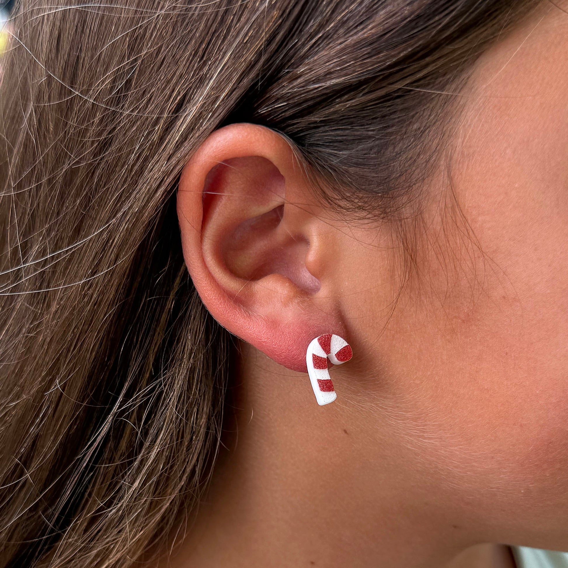A person wearing the candy cane stud earrings for perspective. 