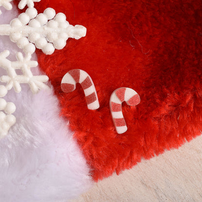 Festive acrylic earrings in the shape of a candy cane on a red plush stocking