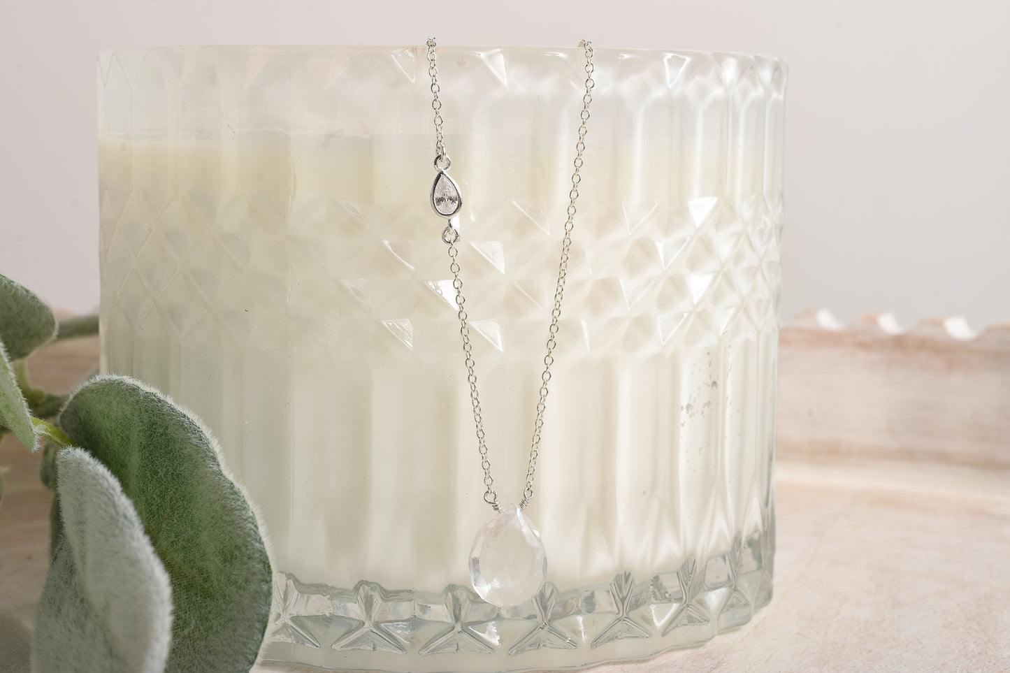 Necklace with a pendant displayed in front of a candle