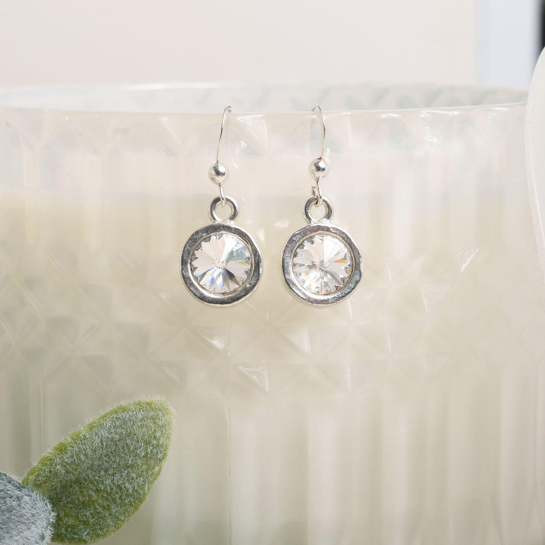 Silver earrings with clear crystals on a white surface