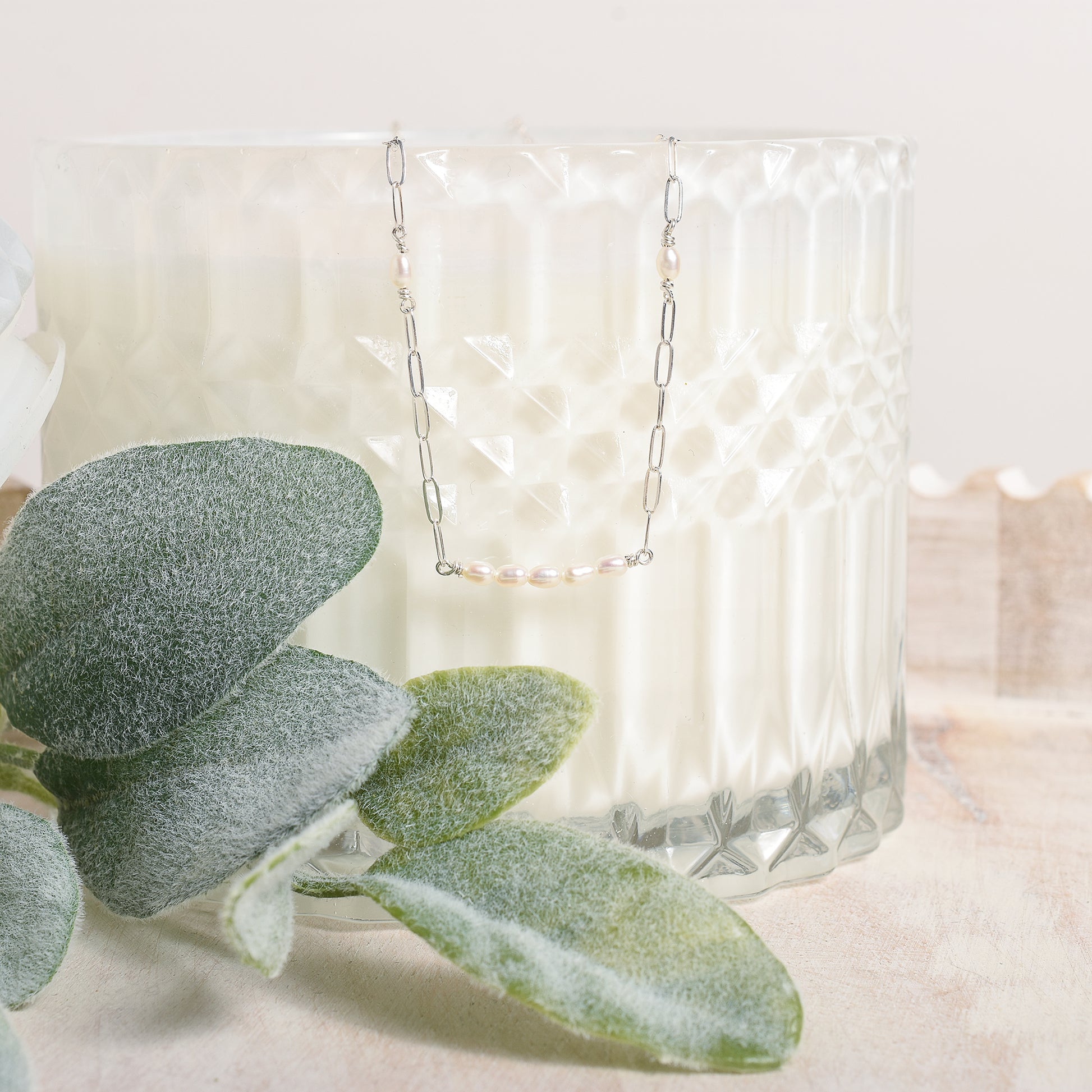 Pearl and silver necklace suspended from an opaque glass