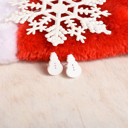 A pair of small white snowman-shaped earrings displayed on a red fuzzy surface with a white snowflake and a cream-colored textured background.