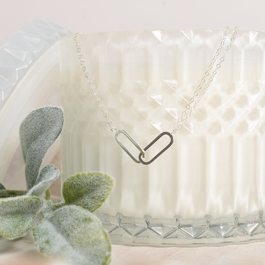 Necklace with a unique pendant design on a textured white surface with a plant.