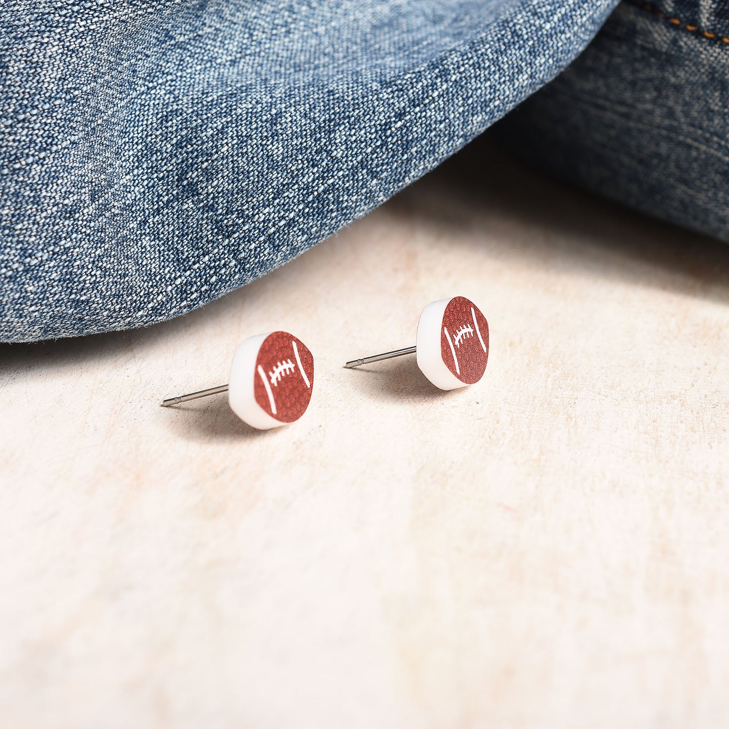 A pair of stainless steel stud earrings in a football shape.