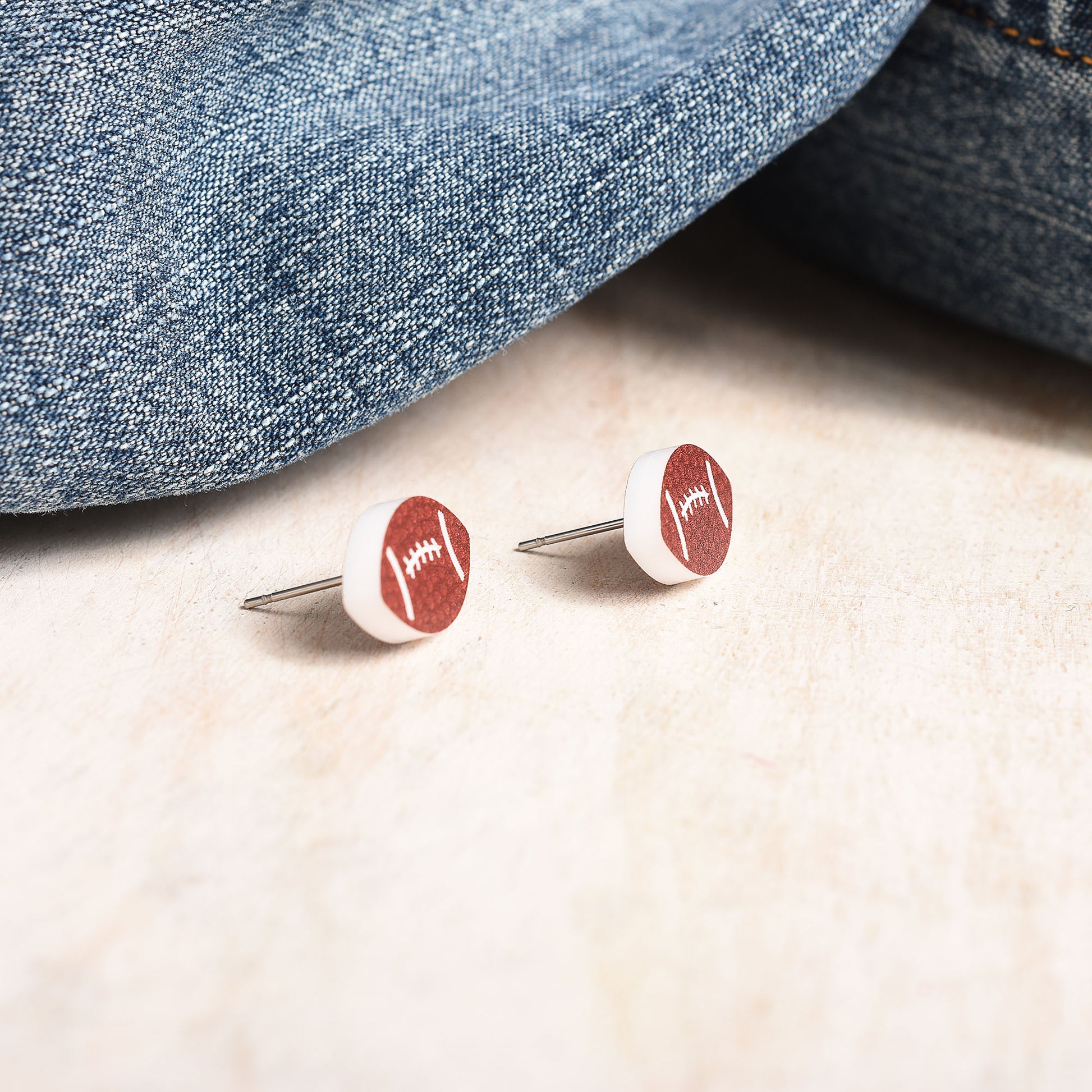 A pair of stainless steel stud earrings in a football shape.