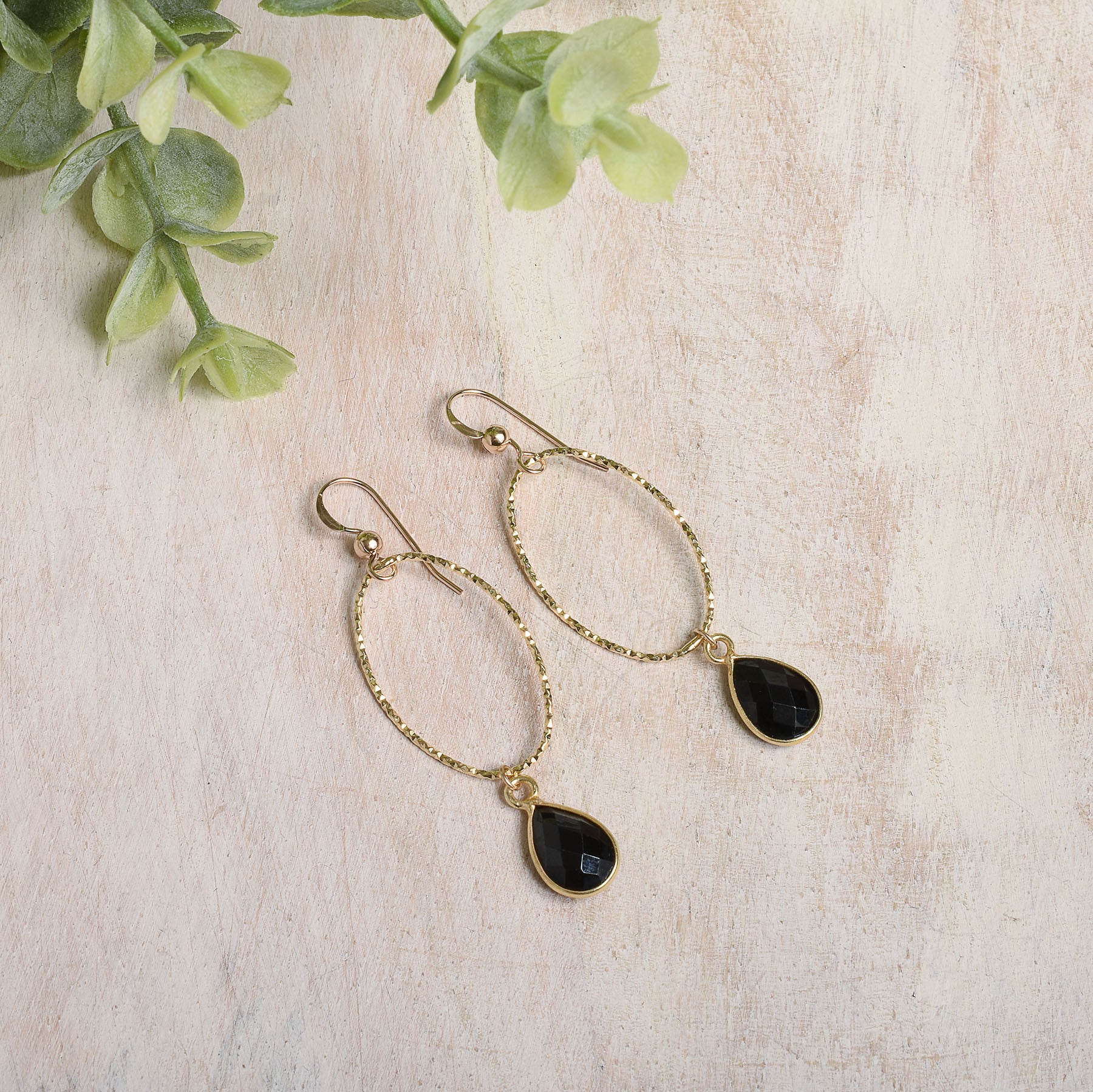 Gold-filled earrings with black spinel teardrop stones on a light background