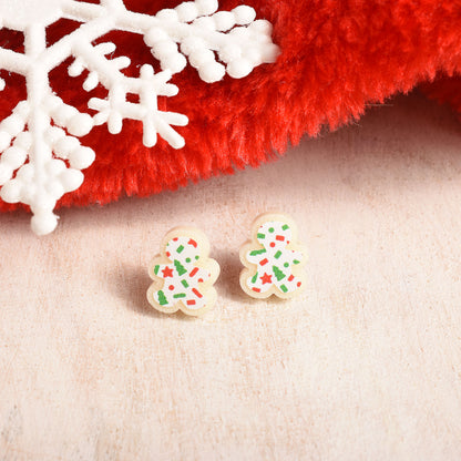Cute gingerbread cookie earrings next to a red stocking and white snowflake.