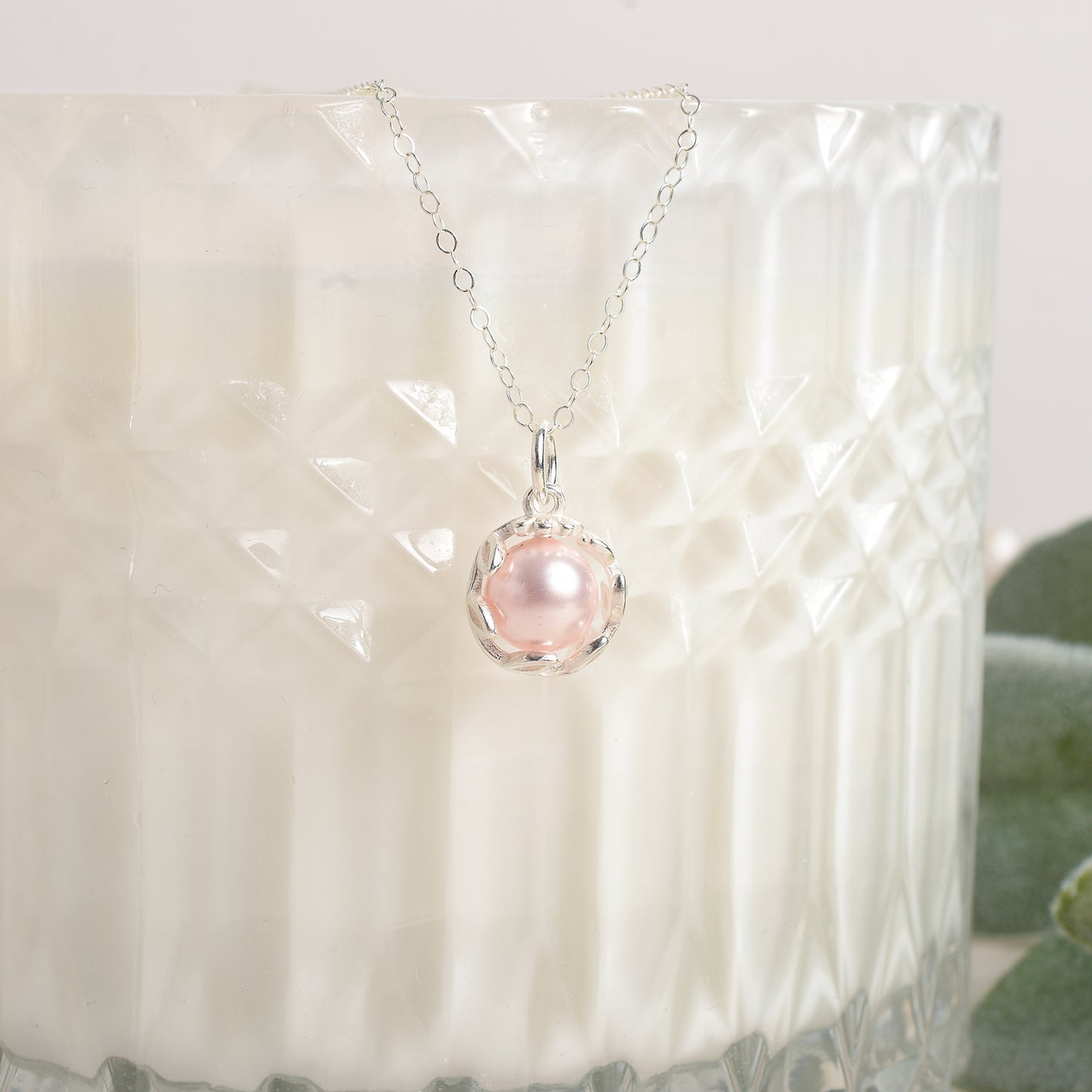 Necklace with a pink pearl pendant on a textured white surface