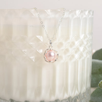Necklace with a pink pearl pendant on a textured white surface