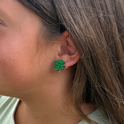 A close-up side profile of a girl wearing a small green glittery shamrock stud earring.