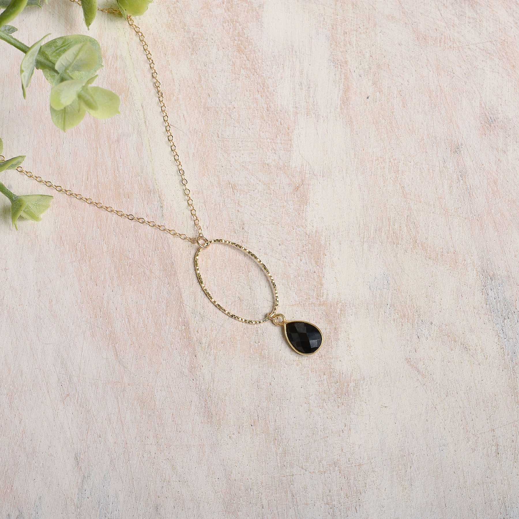 Gold-filled necklace with a black spinel drop on a light background