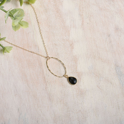 Gold-filled necklace with a black spinel drop on a light background
