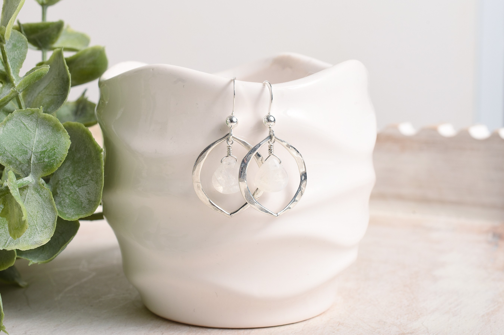 Silver drops accented by rainbow moonstone in dangly earrings suspended from a cup.