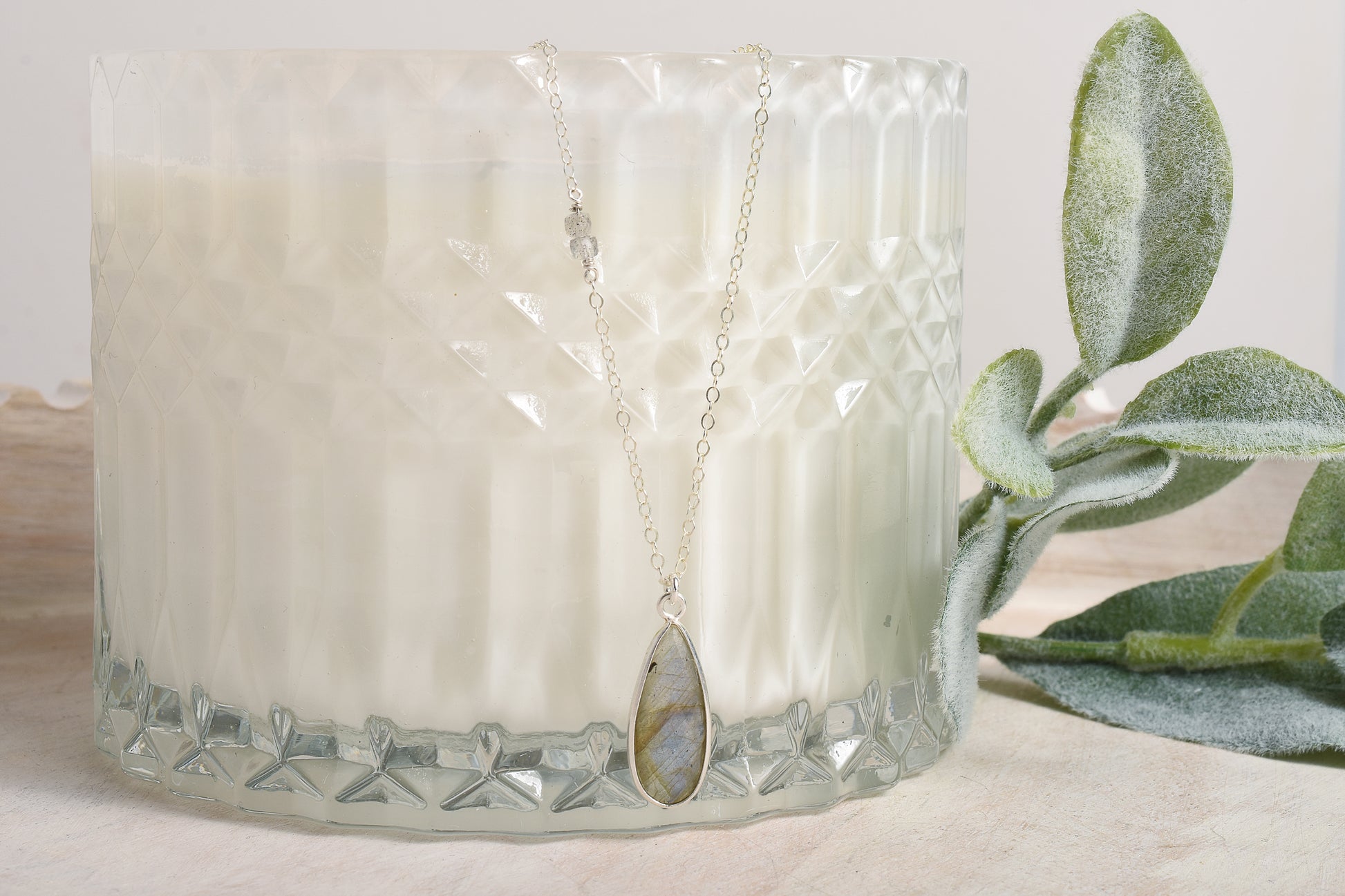 Necklace with a gemstone pendant displayed in front of a candle