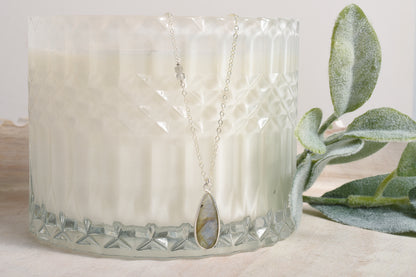 Necklace with a gemstone pendant displayed in front of a candle