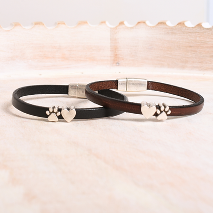 Two leather bracelets with metal clasps and paw print designs on a light background