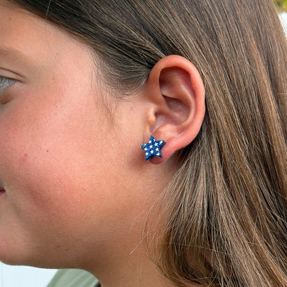 A close-up side profile of a person wearing a small star-shaped stud earring with a blue and white star-and-stripe pattern.