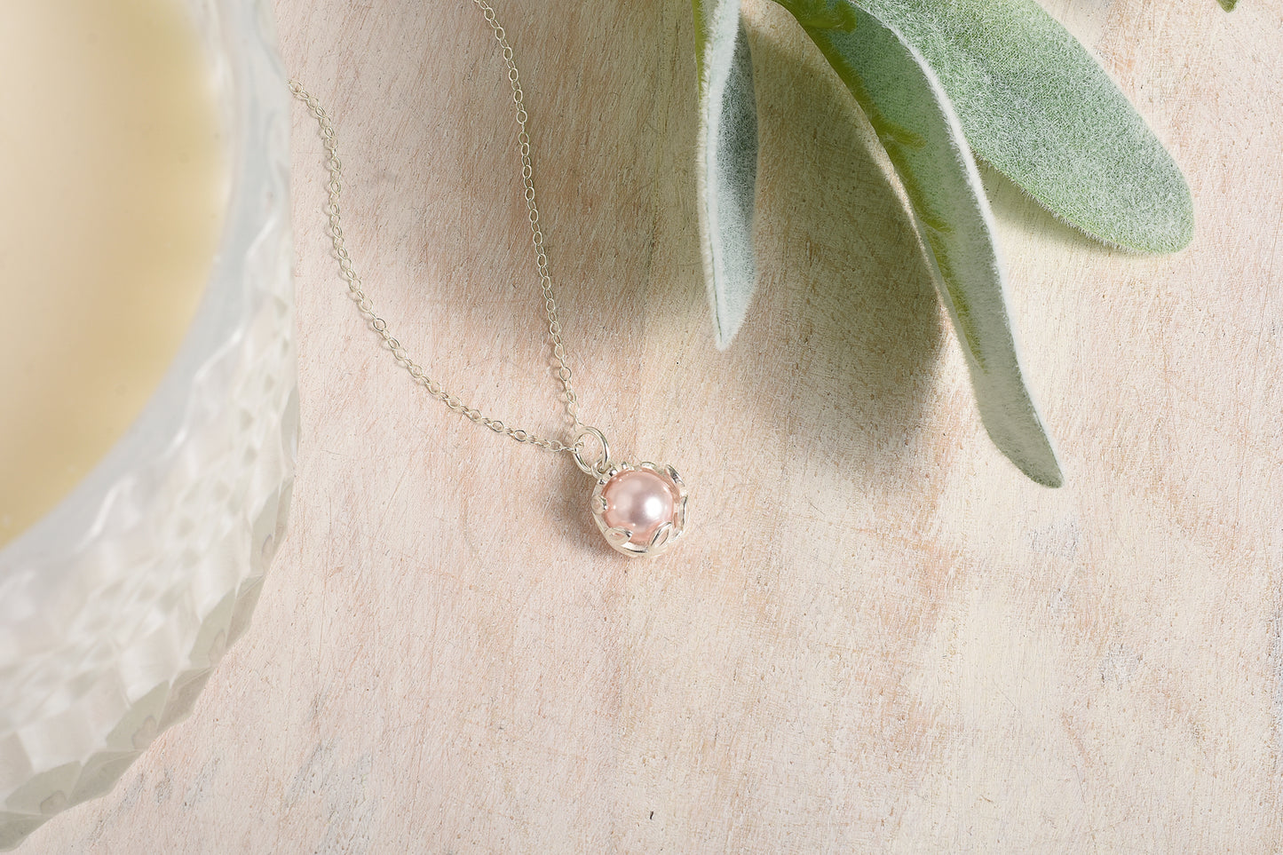 Delicate necklace with a pink pendant on a soft background