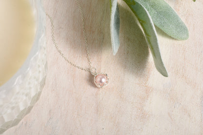 Delicate necklace with a pink pendant on a soft background