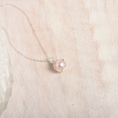 Necklace with a pink pearl pendant on a wood background