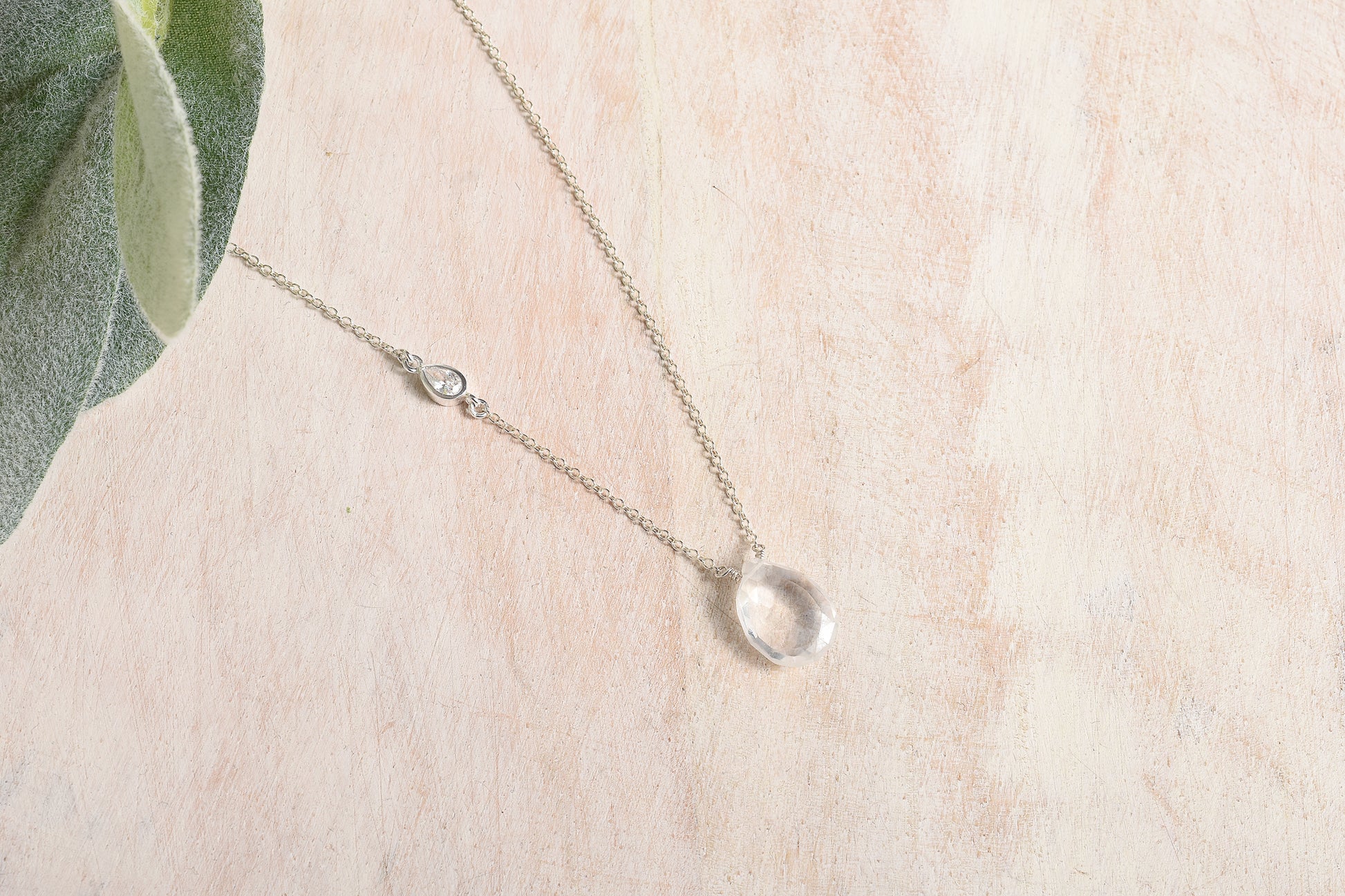 Delicate silver necklace with a small pendant on a light background