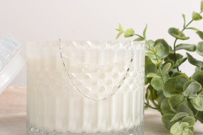 The Eva Necklace hanging from a candle