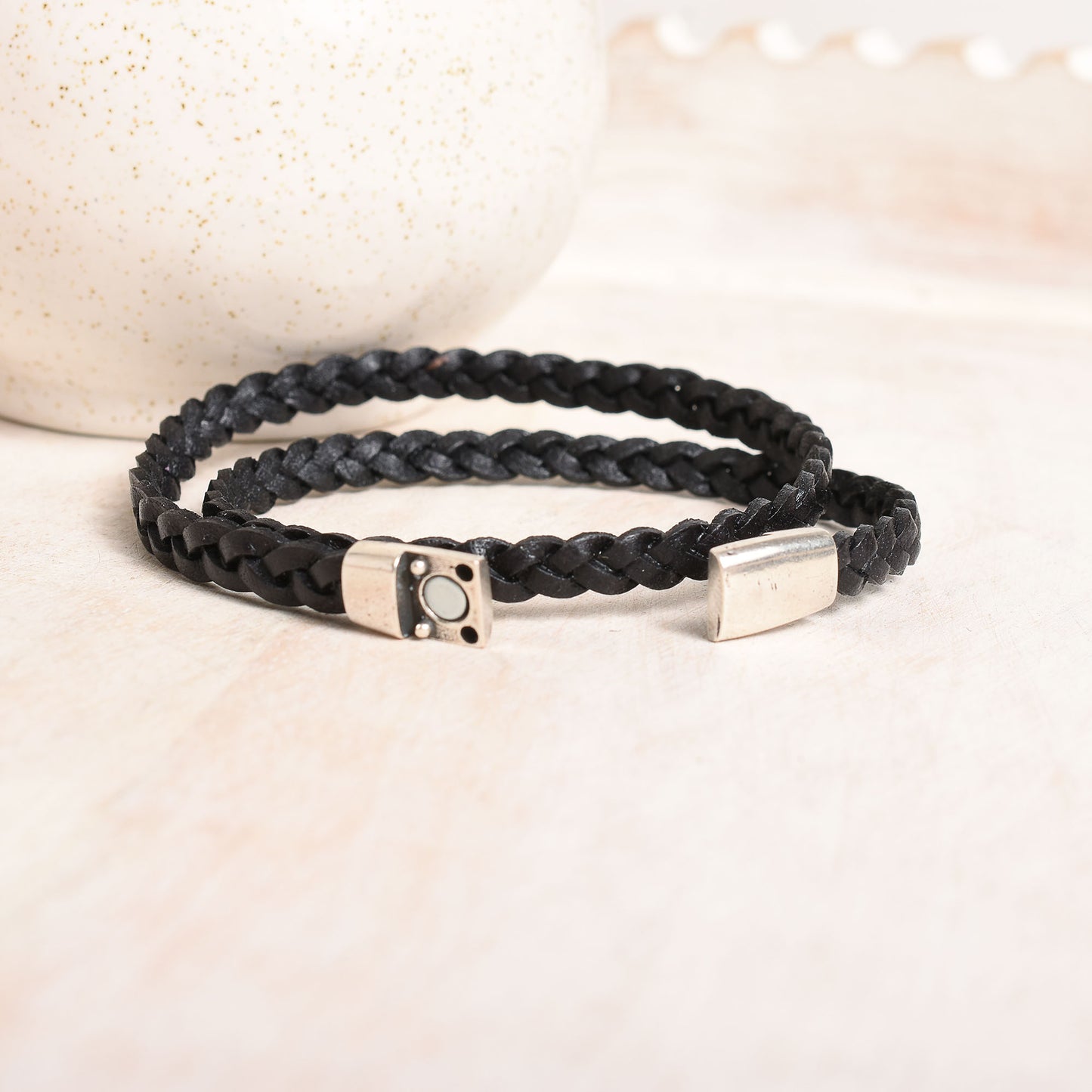 A black braided leather bracelet with a silver-toned magnetic clasp featuring a double wrap style.