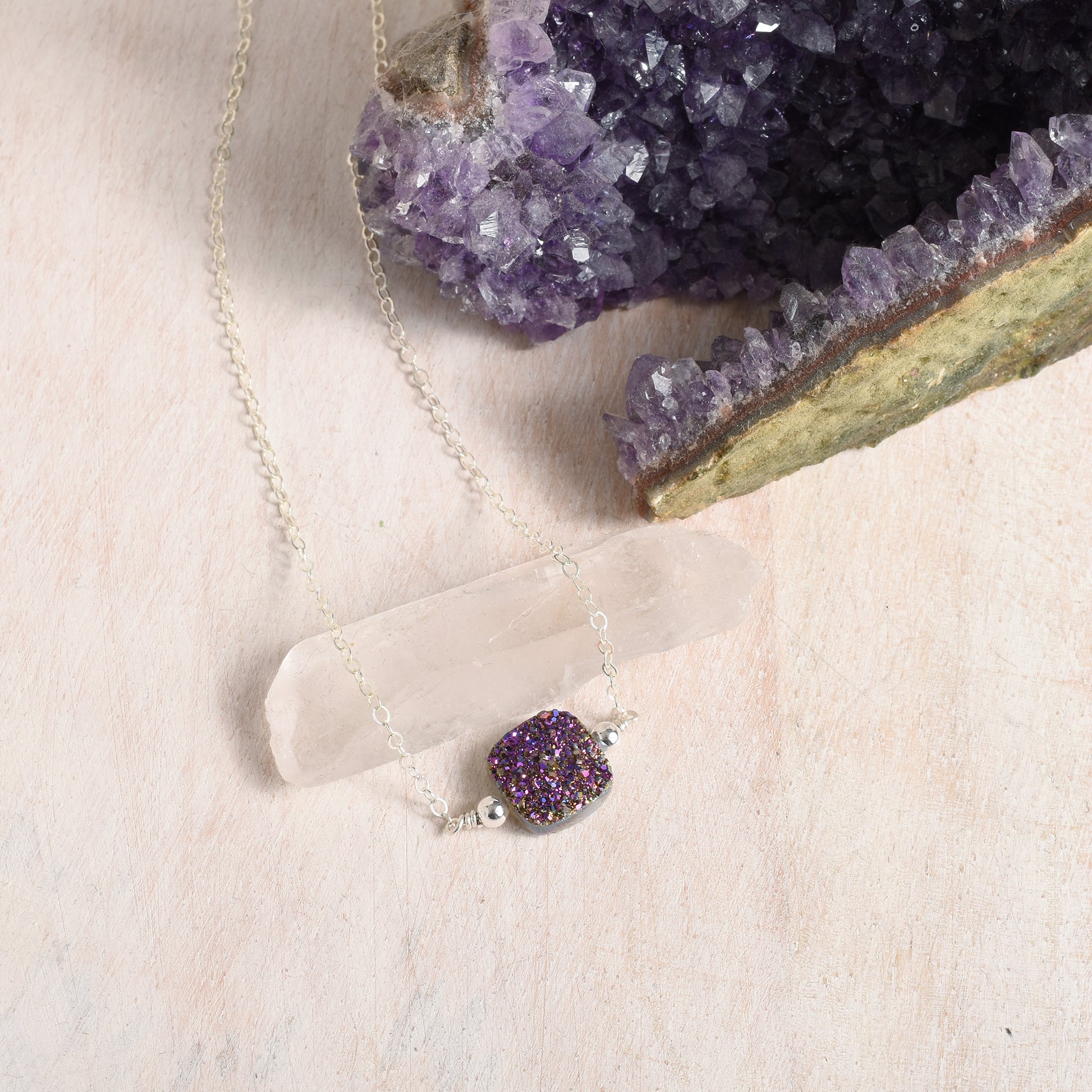 Necklace with a purple gemstone pendant on a beige surface 